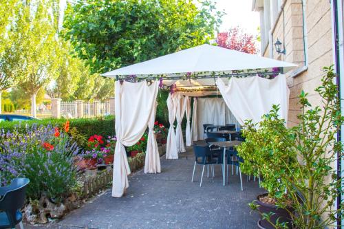 un patio con sombrilla blanca, mesas y sillas en Hostal La Llave, en Mave