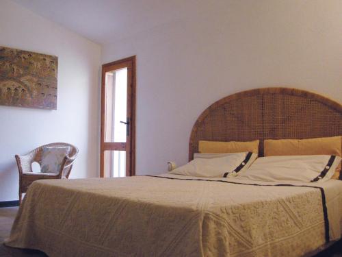 a bedroom with a large bed and a chair at via dei gerani in Solanas