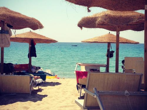 a beach with umbrellas and chairs and the ocean at via dei gerani in Solanas