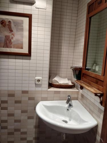 y baño con lavabo blanco y espejo. en Hostal agripino y Restaurante asiático, en Mora