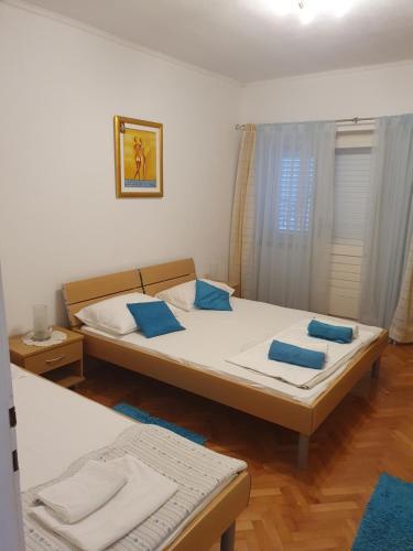 Apartments Jerković Drašnice-3bd في Drašnice: غرفة نوم بسريرين مع وسائد زرقاء