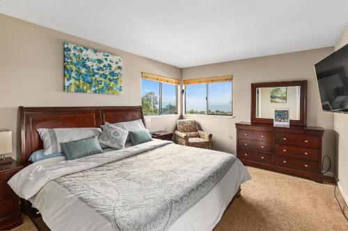 um quarto com uma cama, uma cadeira e janelas em Spectacular Views - Walk to Cannery Row and the Aquarium em Pacific Grove