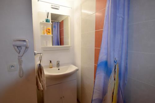 baño con lavabo y cortina de ducha en Chez Patrick, en Grandcamp-Maisy