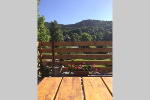 a wooden table in front of a fence with flowers at SanMari_forest in Ledenice