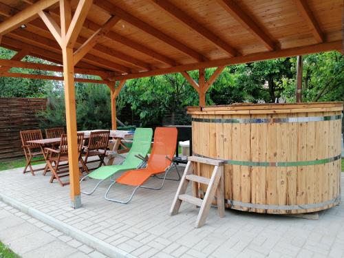 a wooden gazebo with tables and chairs and a hot tub at Apollo Vendégház in Edelény