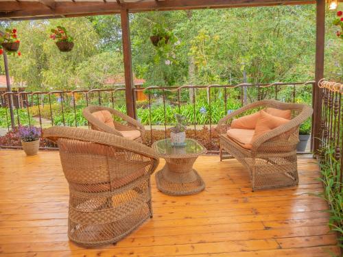 a patio with wicker chairs and a table on a deck at Hotel de Montaña Suria in San Gerardo de Dota