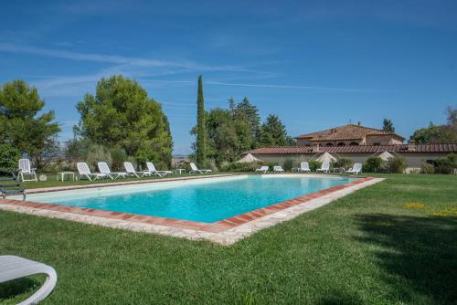 a swimming pool in a yard with chairs and a house at Il Canto del Sole in Monteroni dʼArbia