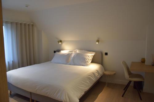 1 cama con sábanas blancas y almohadas en una habitación en B&B Villa Mimosa, en Neerpelt
