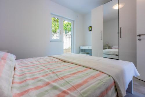 a white bedroom with a bed and a window at NeMo in Povile