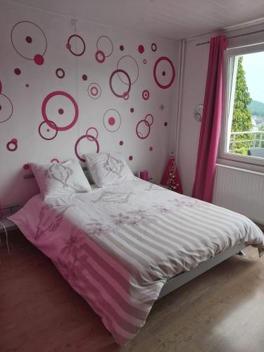 a bedroom with a bed with a pink wall with circles at El Corazon in Stavelot