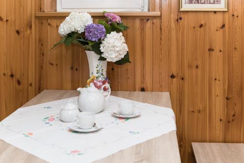 a table with a vase of flowers and tea cups at Casa Flora in Treppo Grande
