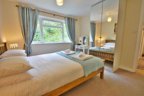 a bedroom with a bed and a window and a mirror at The Paddocks Cottages in Symonds Yat