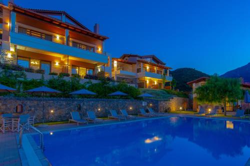 a villa with a swimming pool at night at Αlissachne Suites in Limnionas