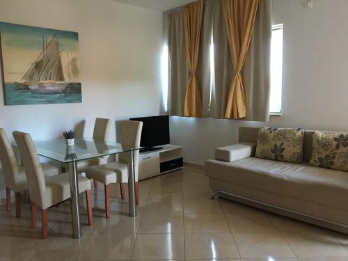 ein Wohnzimmer mit einer Couch, einem Tisch und einem Fernseher in der Unterkunft Apartments Sanja in Hvar
