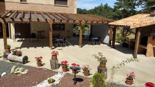a patio with potted plants and a wooden pergola at Hotel Rural El Nido de Pinares in Navaleno