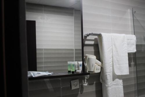 a bathroom with a mirror and towels on a shelf at City Hôtel - Mauritanie in Nouakchott