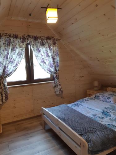 1 dormitorio con 1 cama en una cabaña de madera en Domek na wzgórzu "RYŚ", en Krempna