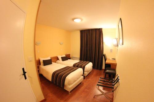 a hotel room with two beds and a desk at Auberge De Bourgogne in Tonnerre