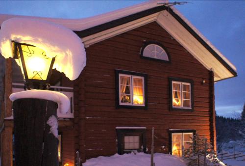 a house with lights in the windows with snow on it at Mannflogården Bed & Breakfast , Sälenfjällen in Sälen
