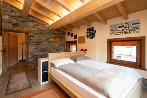 un grande letto in una stanza con un muro di pietra di Hotel Krone a Livigno