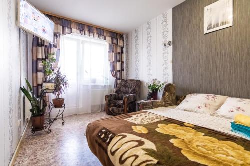 ヴェリーキー・ノヴゴロドにあるApartments Ivushkiのベッドルーム1室(ベッド1台、椅子、窓付)