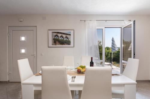 a white dining room with a white table and chairs at Apartments Oliva in Poreč