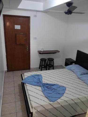 a bedroom with a bed with blue sheets and a table at Hotel Mustang in Sao Paulo