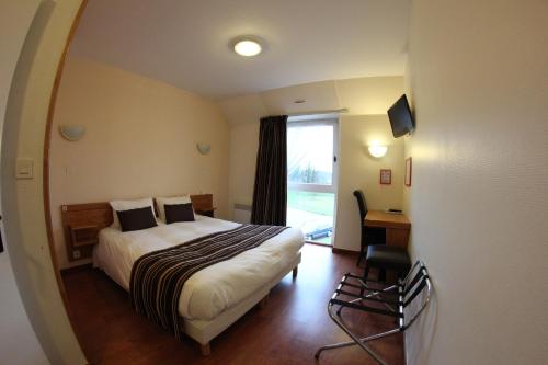 a hotel room with a bed and a desk and a window at Auberge De Bourgogne in Tonnerre