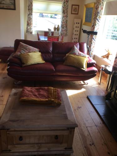 a brown leather couch in a living room with a coffee table at Hornhead Mews, Hornhead in Dunfanaghy
