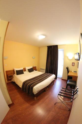 a hotel room with a bed and a chair at Auberge De Bourgogne in Tonnerre
