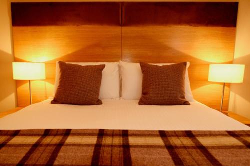 a bedroom with a bed with pillows and two lamps at The Acarsaid - Pitlochry in Pitlochry