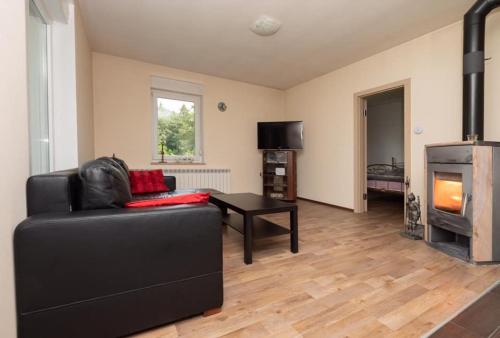 a living room with a black couch and a fireplace at Apartmaji Velikonja in Ajdovščina