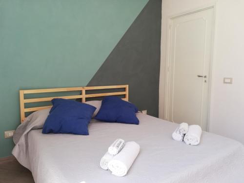 ein Bett mit zwei blauen Kissen und Handtüchern darauf in der Unterkunft Saline nello Stagnone in Marsala