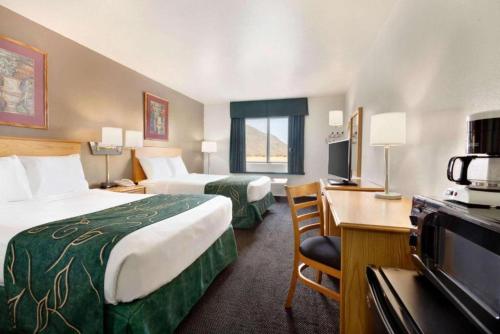 a hotel room with two beds and a desk at Travelodge by Wyndham Yermo in Yermo