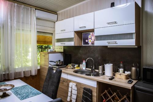 a kitchen with white cabinets and a sink at Villa Apartman in Makó