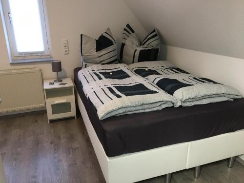 a bed with black and white blankets and pillows at Ferienwohnung „Im Kleinen Löök“ - DG - 2 Zimmer - Balkon - Boxspringbett - 2 TV in Rinteln