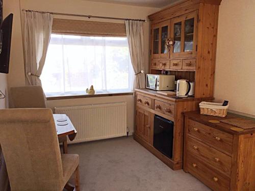 una cocina con armarios de madera y una ventana en Hartpury B&B, en Hartpury