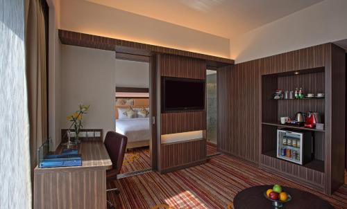 a hotel room with a bedroom with a bed and a desk at Novotel Pune Viman Nagar Road in Pune