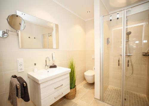 ein Badezimmer mit einem weißen Waschbecken und einer Dusche in der Unterkunft Haus Vier Jahreszeiten in Wangerooge