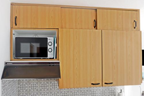 a kitchen with wooden cabinets and a microwave at Schick und freundlich, zentral, modernes Studio - C5 in St. Moritz