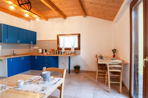 Una cocina con gabinetes azules y una mesa y sillas. en La Casa Del Sole, en Gradara