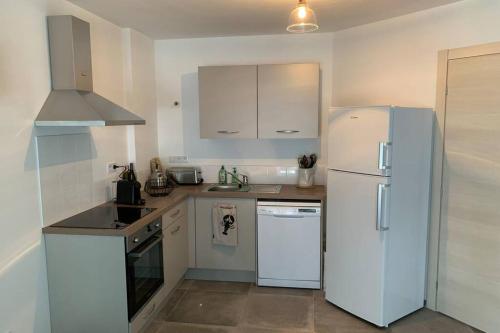 Il comprend une cuisine équipée d'un réfrigérateur blanc et d'une cuisinière. dans l'établissement Appartement neuf sur Plage de Calvi Vue Mer, à Calvi