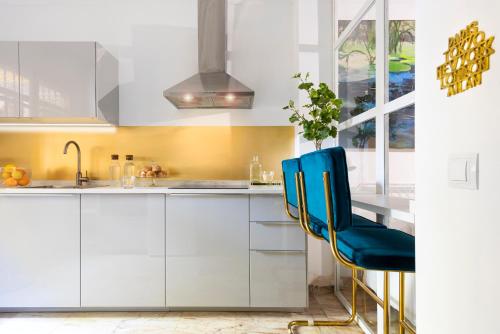 una cocina con armarios blancos y una silla azul en UNICO ALCAZAR Apartment, en Sevilla