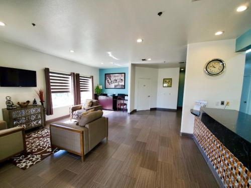 a living room with a couch and a clock on a wall at Super 8 by Wyndham Forney/East Dallas in Forney