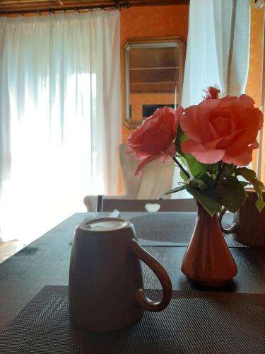 un jarrón de flores y una taza sobre una mesa en B&B La Locanda del Cinghiale, en Aurano