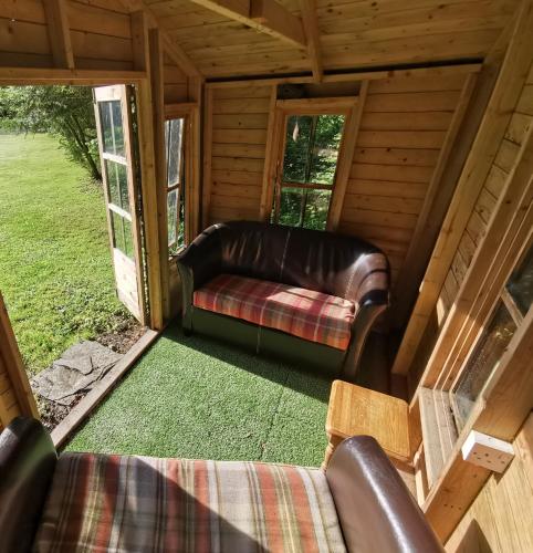a living room with leather furniture in a cabin at Ty Mawr Country Hotel & Restaurant in Carmarthen