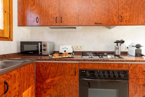 a kitchen with wooden cabinets and a stove top oven at 21 Sleeps Private Pool Villa & BBQ Near Barcelona in Rocafort
