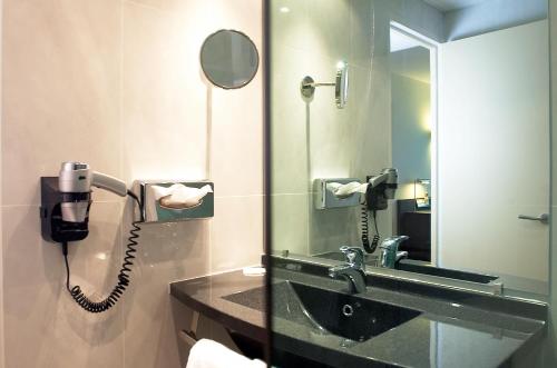 - une salle de bains avec un téléphone à côté d'un lavabo dans l'établissement Oceania Quimper, à Quimper
