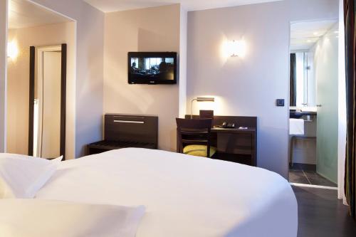 a hotel room with a bed and a desk and a television at Escale Oceania Vannes Centre in Vannes