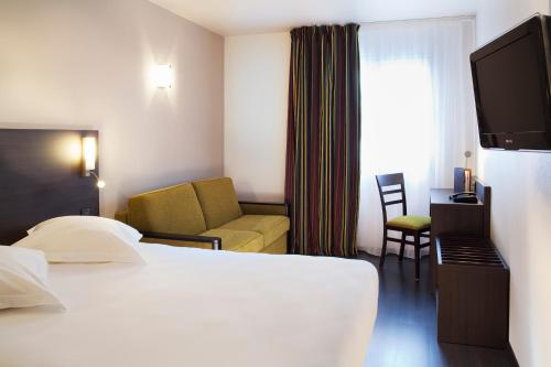 a hotel room with a bed and a chair at Escale Oceania Vannes Centre in Vannes